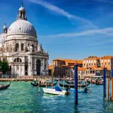 En gondol färdas på Venedigs kanaler framför den ståtliga kyrkan Santa Maria della Salute. En perfekt dag för en resa med tåg till Venedig.
