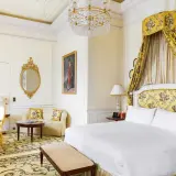Ett lyxigt hotellrum i London med en stor säng, en sittgrupp och en utsmyckad spegel.