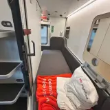 Sovkabin i en Nightjet för Interrail. En orange filt med texten "Dream ov. Enjoy tomorow." ligger på en bädd.