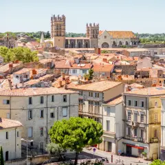 En vy över mysiga byar i Languedoc med sina terrakottafärgade tak och en imponerande katedral i bakgrunden.