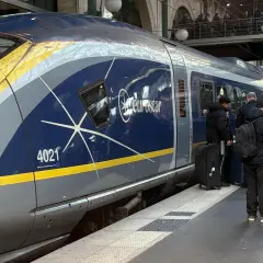 Eurostar-tåget står redo för en resa i Europa. Passagerare med bagage väntar på perrongen.