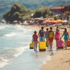 En familj med barn går längs stranden med resväskor, redo för en resa billigt i Europa.