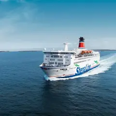 Stena Line-färja på väg till Danmark, med en stor vit skrov och blå linjer, lämnar ett vitt spår i det blå havet under en klarblå himmel.