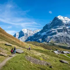 Vandrare på en stig i Alperna, en fantastisk vandring i Europa med snöklädda berg och charmiga hus.