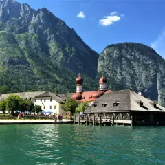 Vacker badsemester i Tyskland vid en turkos sjö med berg och en kyrka i bakgrunden.
