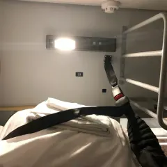 En bädd i en couchette train med vita lakan, handdukar och ett säkerhetsbälte.