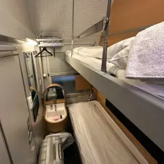 Sovhytt på ett nattåg Stockholm med våningssängar, handfat och bagage.