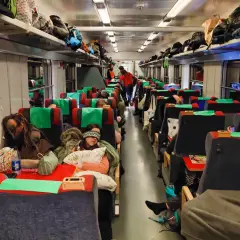 Resenärer sover i en sj sovvagn 2 klass. Bagage ligger på hyllorna ovanför sätena.