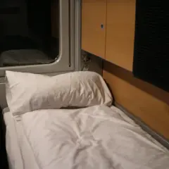 En bäddad sovkupé på ett sj nattåg genom Europa. Vita lakan och en kudde väntar.