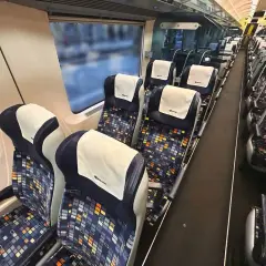 Tomma säten i en nattåg till München. Mörka säten med färgglatt mönster och vita nackstöd.