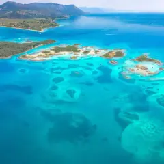 Blågrönt vatten omger gröna öar och skärgårdar. En drömresa till Evia, Grekland, med dess turkosa laguner och berg i bakgrunden.