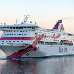 Silja Line-färja på en kryssning Stockholm-Åbo. En stor vit passagerarfärja med rosa dekorationer glider fram på vattnet i solnedgången.
