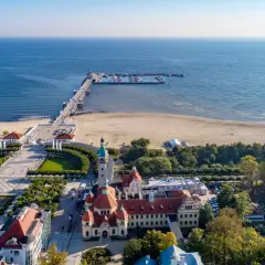 Sopot, Polens riviera, med sin berömda pir som sträcker sig ut i Östersjön. En vacker strand och grönskande parker omger de historiska byggnaderna.
