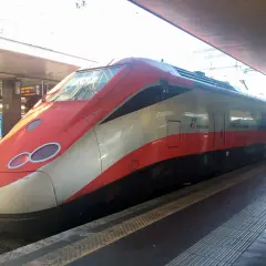 Röda och vita höghastighetståget Frecciarossa står vid perrongen, redo för resan. Snart bär det av med tåg till Florens.
