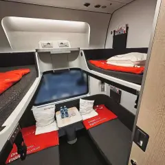 Sovkabin i biltåg mellan Hamburg och Innsbruck. Två våningssängar med röda filtar och kuddar.
