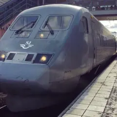 Grått SJ-tåg står vid perrongen, redo för en interrail-resa genom Sverige.
