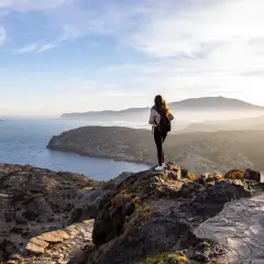 Ensam vandrare njuter av den dramatiska kustlinjen vid Costa Brava. Solen går ner över bergen och havet.