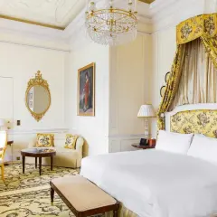 Ett lyxigt hotellrum i London med en stor säng, en sittgrupp och en utsmyckad spegel.