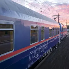 Nattåg köpenhamn paris, Nightjet-tåget susar fram genom ett vackert kvällslandskap med rosa moln.