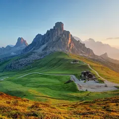 Vacker solnedgång över Dolomiterna, perfekt för en vandring. Grönskande kullar och dramatiska bergstoppar.