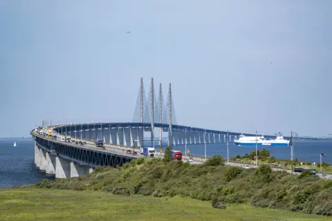 Öresundsbron, bron till Danmark, med bilar och en färja i Öresund.