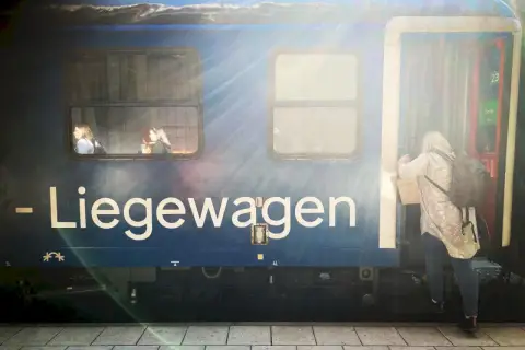 En kvinna kliver på ett tåg med destination Berlin. Två passagerare tittar ut genom fönstret.