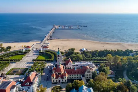 Sopot, Polens riviera, med sin berömda pir som sträcker sig ut i Östersjön. En vacker strand och grönskande parker omger de historiska byggnaderna.