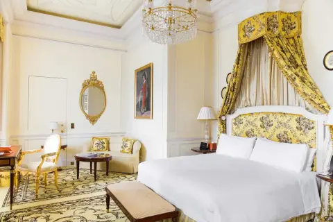 Ett lyxigt hotellrum i London med en stor säng, en sittgrupp och en utsmyckad spegel.