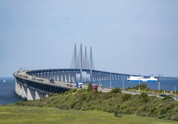 Öresundsbron, bron till Danmark, med bilar och en färja i Öresund.