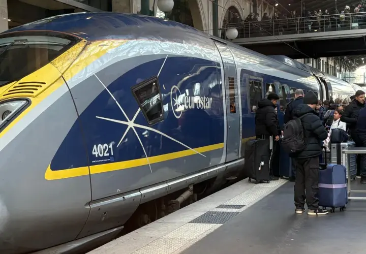 Eurostar-tåget står redo för en resa i Europa. Passagerare med bagage väntar på perrongen.