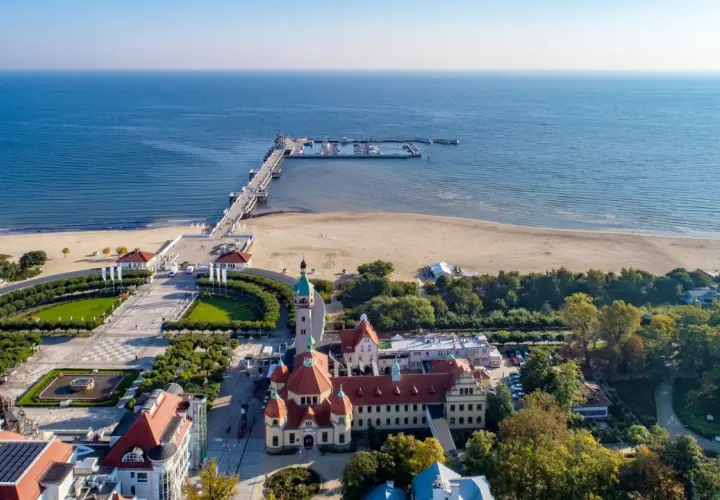 Sopot, Polens riviera, med sin berömda pir som sträcker sig ut i Östersjön. En vacker strand och grönskande parker omger de historiska byggnaderna.