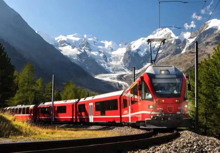 Rött tåg i alpint landskap med snöklädda berg. En resa genom norra Italien med fantastisk utsikt.
