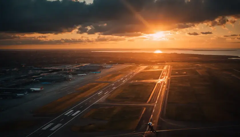 Solnedgång över flygplatsen. En känsla av att ta ett tåg till Kastrup, med flygplan som väntar på start.