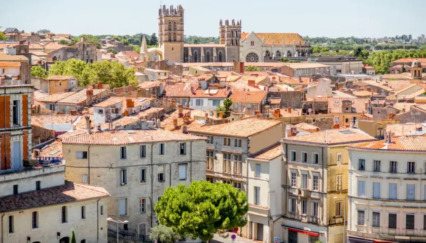 En vy över mysiga byar i Languedoc med sina terrakottafärgade tak och en imponerande katedral i bakgrunden.