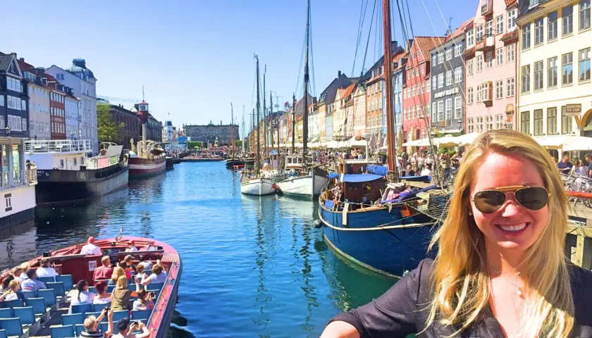 En glad kvinna njuter av en solig dag i Köpenhamn. En båttur på kanalen är ett perfekt sätt att uppleva staden, kanske efter en resa med tåg för en härlig weekend.