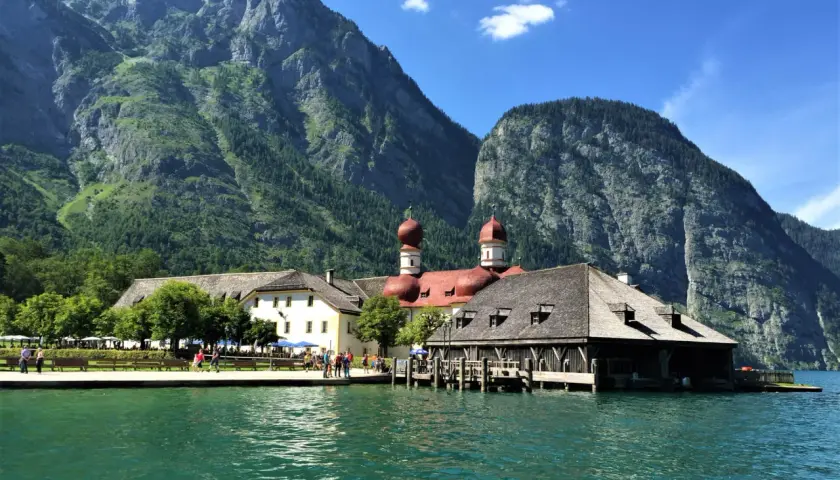 Vacker badsemester i Tyskland vid en turkos sjö med berg och en kyrka i bakgrunden.