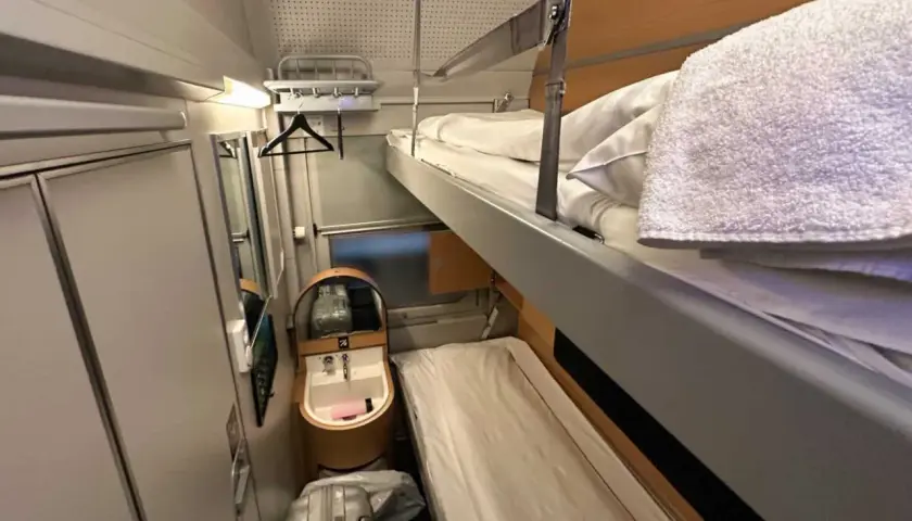 Sovhytt på ett nattåg Stockholm med våningssängar, handfat och bagage.