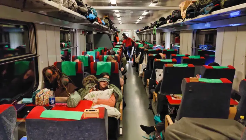 Resenärer sover i en sj sovvagn 2 klass. Bagage ligger på hyllorna ovanför sätena.