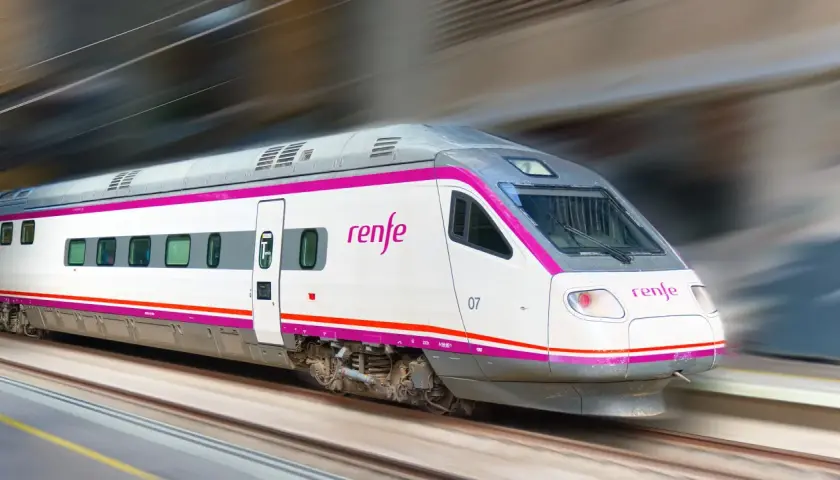 Ett modernt Renfe-tåg i Spanien susar fram längs spåren, med sina distinkta lila och vita färger.