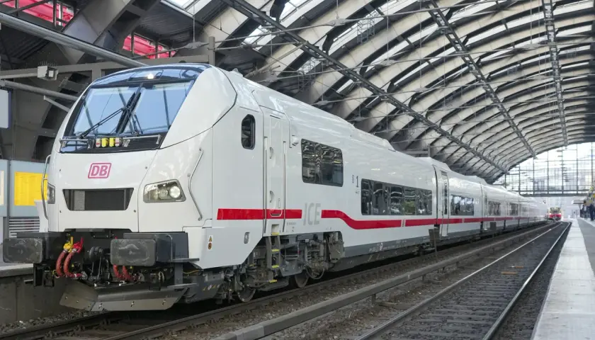 Ett modernt vitt ICE-tåg med röda detaljer står på en station i Hamburg. Tåget är redo att ta passagerare på en resa.