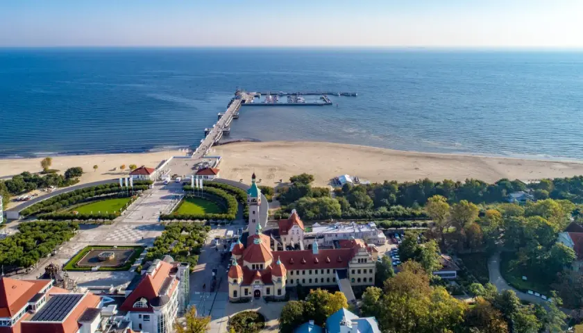 Sopot, Polens riviera, med sin berömda pir som sträcker sig ut i Östersjön. En vacker strand och grönskande parker omger de historiska byggnaderna.