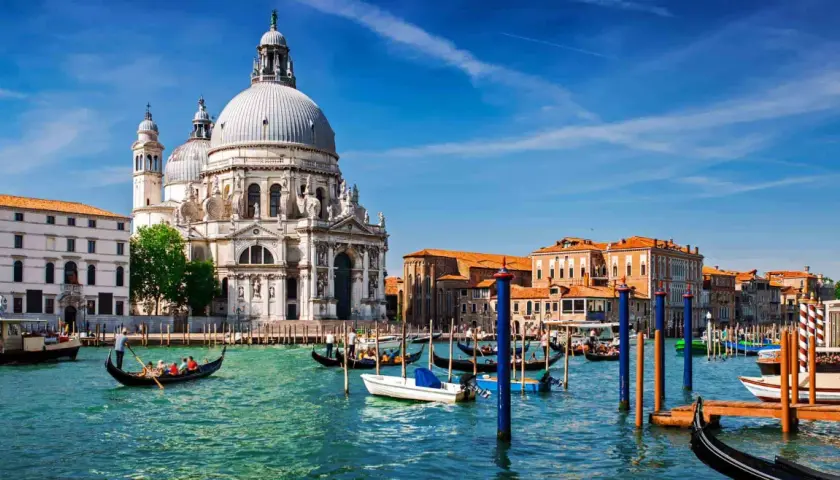 En gondol färdas på Venedigs kanaler framför den ståtliga kyrkan Santa Maria della Salute. En perfekt dag för en resa med tåg till Venedig.