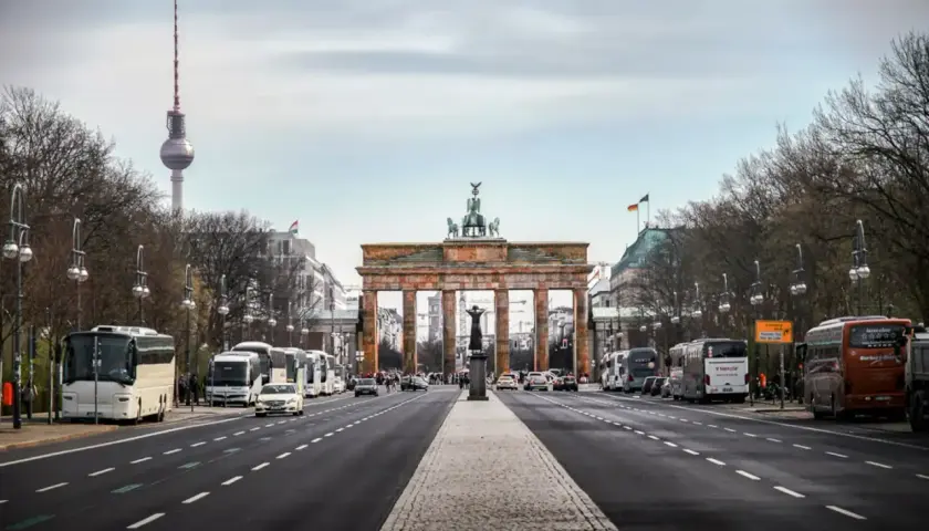 Brandenburger Tor och TV-tornet syns tydligt under en resa till Berlin. Bussar och bilar trafikerar gatan.