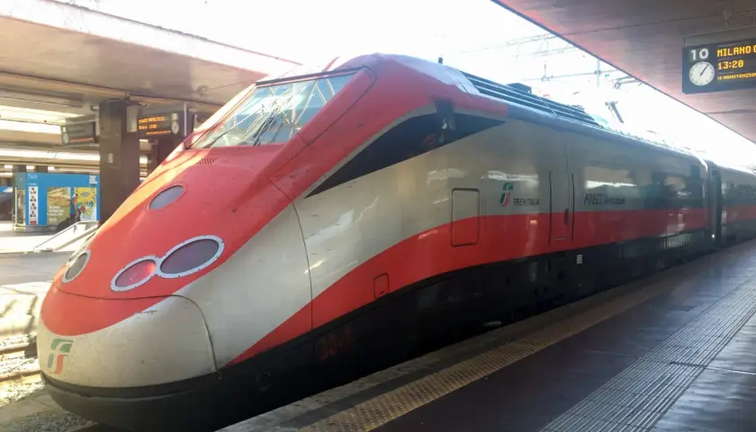 Röda och vita höghastighetståget Frecciarossa står vid perrongen, redo för resan. Snart bär det av med tåg till Florens.