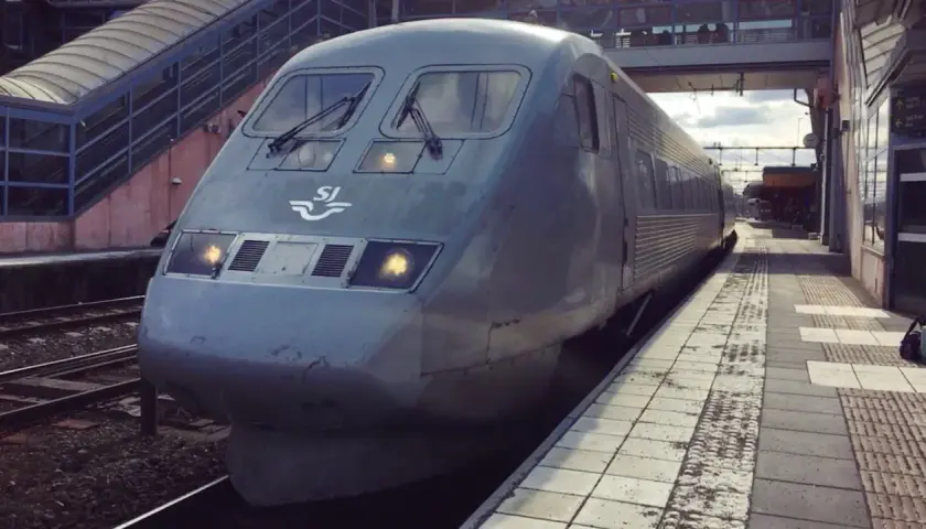 Grått SJ-tåg står vid perrongen, redo för en interrail-resa genom Sverige.