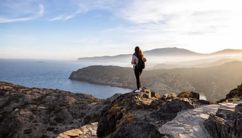 Ensam vandrare njuter av den dramatiska kustlinjen vid Costa Brava. Solen går ner över bergen och havet.