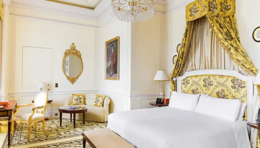 Ett lyxigt hotellrum i London med en stor säng, en sittgrupp och en utsmyckad spegel.