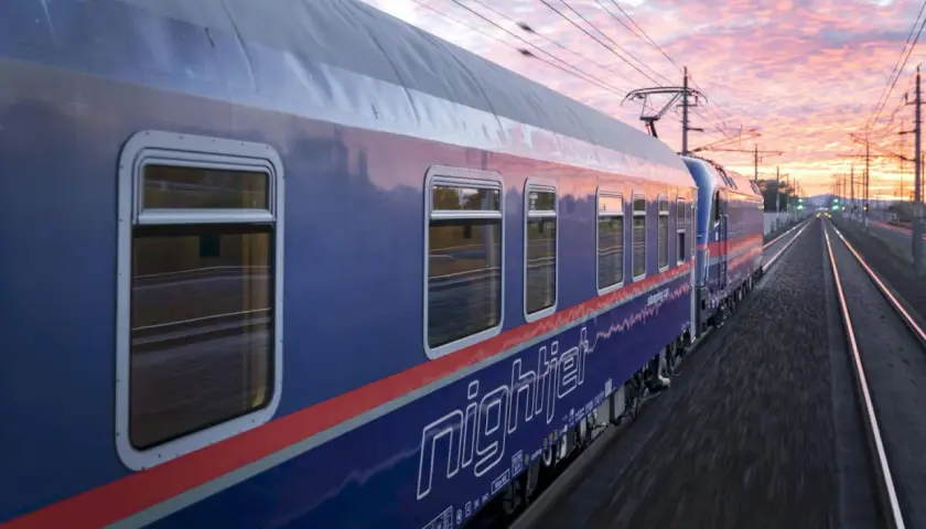 Nattåg köpenhamn paris, Nightjet-tåget susar fram genom ett vackert kvällslandskap med rosa moln.