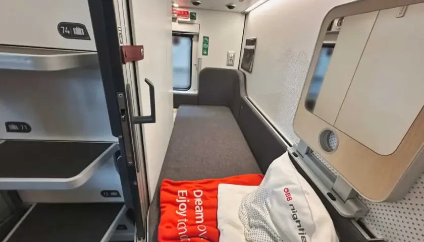 Sovkabin i en Nightjet för Interrail. En orange filt med texten "Dream ov. Enjoy tomorow." ligger på en bädd.