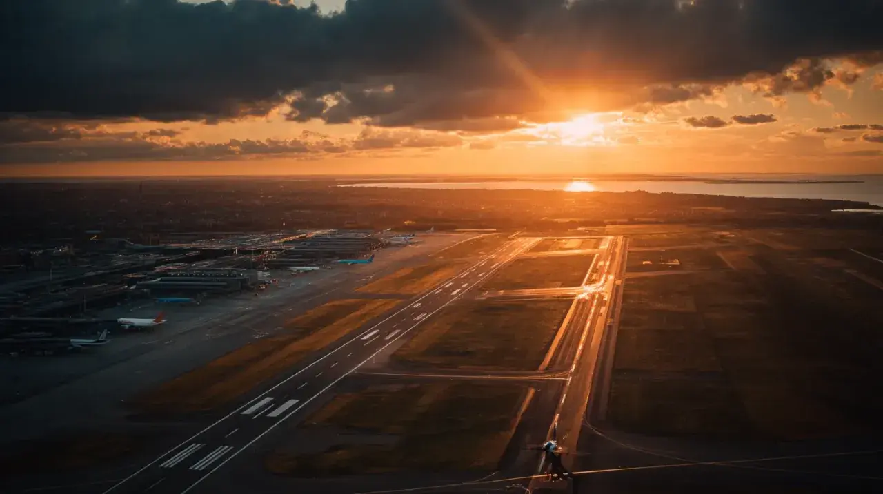 Solnedgång över flygplatsen. En känsla av att ta ett tåg till Kastrup, med flygplan som väntar på start.